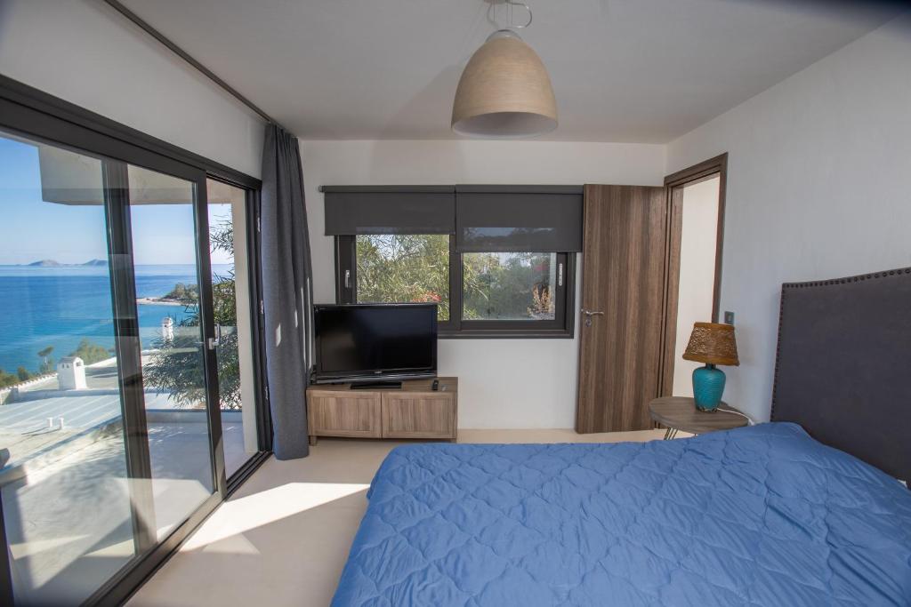 a bedroom with a blue bed and a television at Raise Spetses Sea View Villa in Spetses