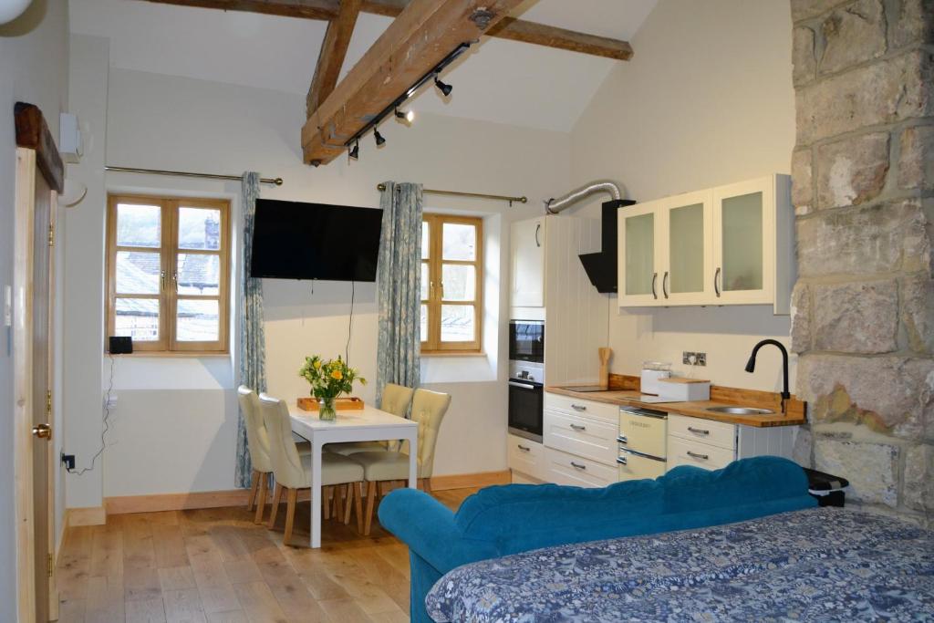 a kitchen with a table and a blue couch in a room at Hebble end works apartment 3 in Hebden Bridge