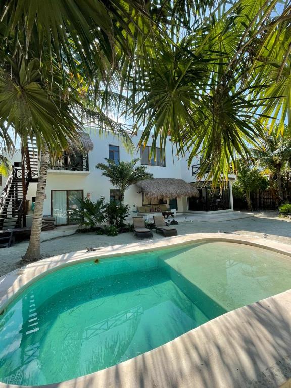 a swimming pool in front of a house with palm trees at Luxury Ocean Front Villa - Adults Only in Holbox Island