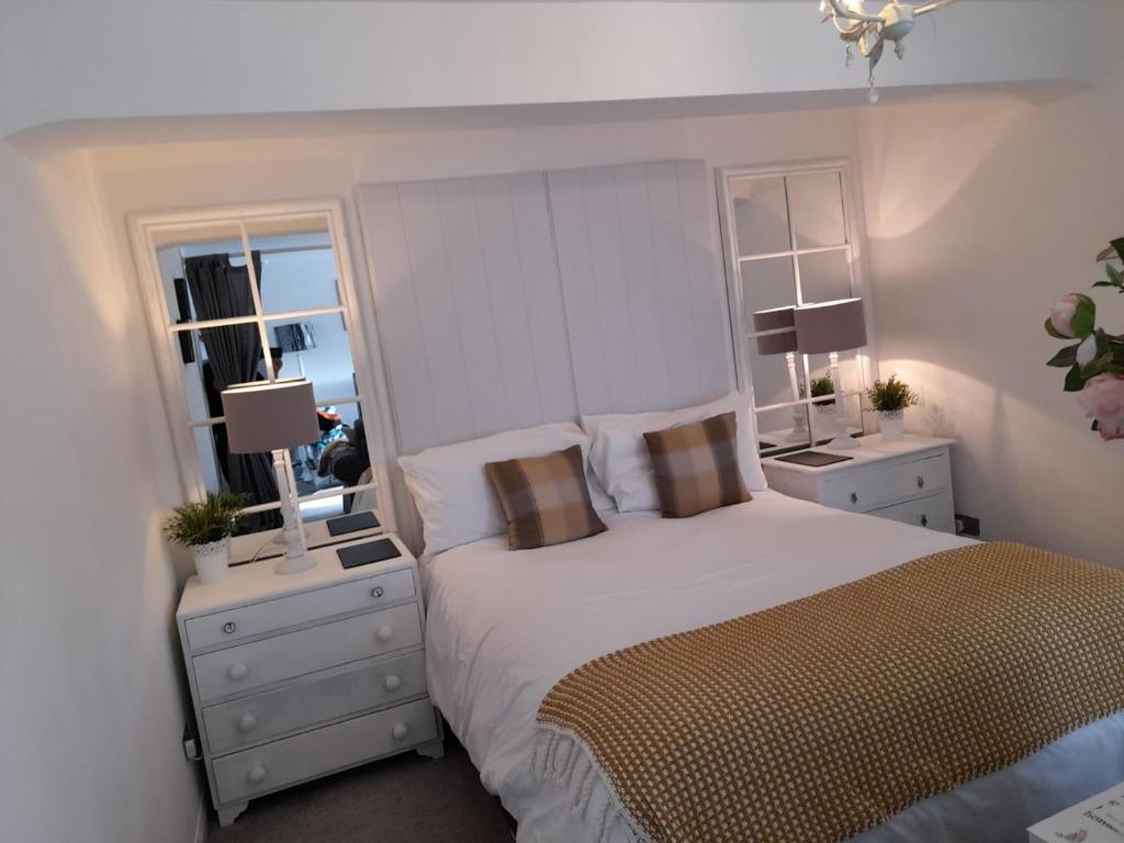 een slaapkamer met een bed met 2 nachtkastjes en 2 ramen bij The Studio in Windermere