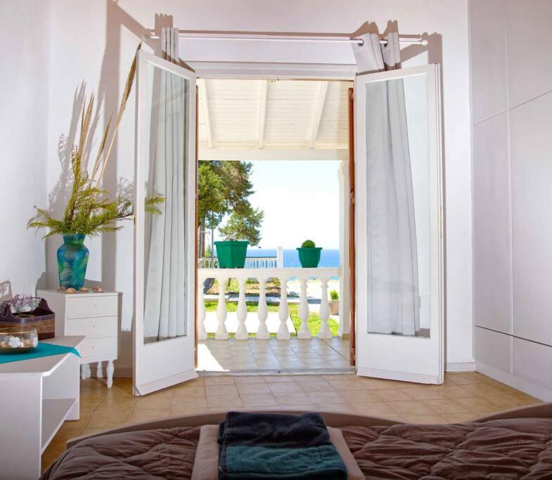 a bedroom with an open door to a balcony at Villa Elpida in Agios Georgios