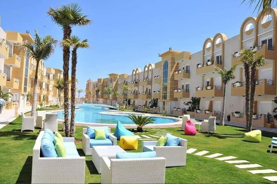 a resort yard with couches and palm trees and a pool at GHS app in Akouda