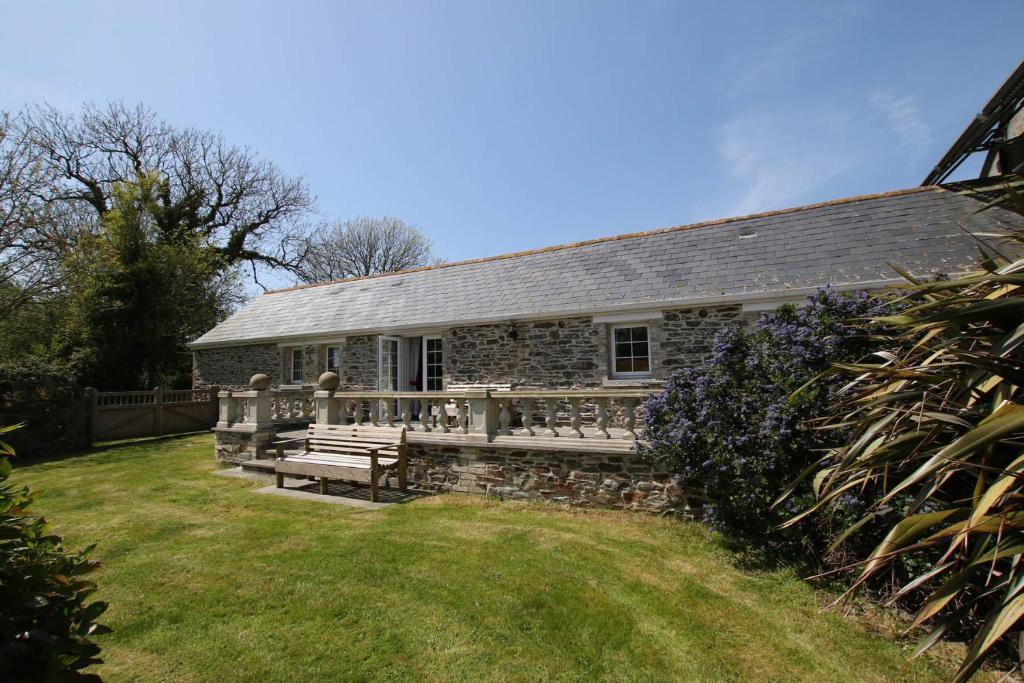 una casa de piedra con un banco en el patio en Chy un Lur Rural cottage en Truro