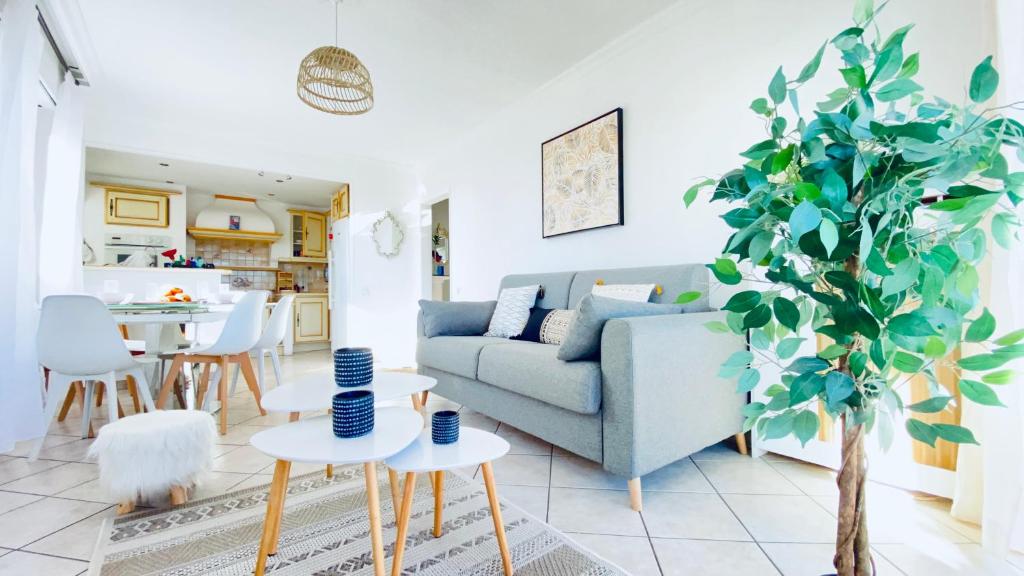 un salon avec un canapé bleu et un arbre dans l'établissement DELMAS - T3 VUE MER - Parc, Base loisirs, Bus Sophia Antipo, à Antibes