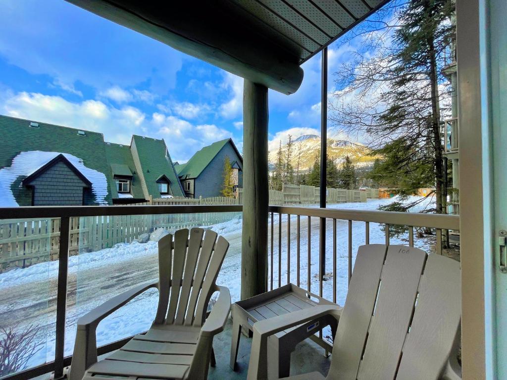 two chairs sitting on a porch in the snow at Windtower Lodge FullKitchen-Kingbed Suite-MntView-UGParking-Walk2DT in Canmore