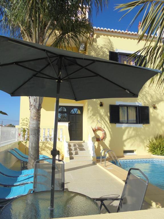 a table with an umbrella in front of a house at Apartamentos Paradise Fuseta in Fuzeta