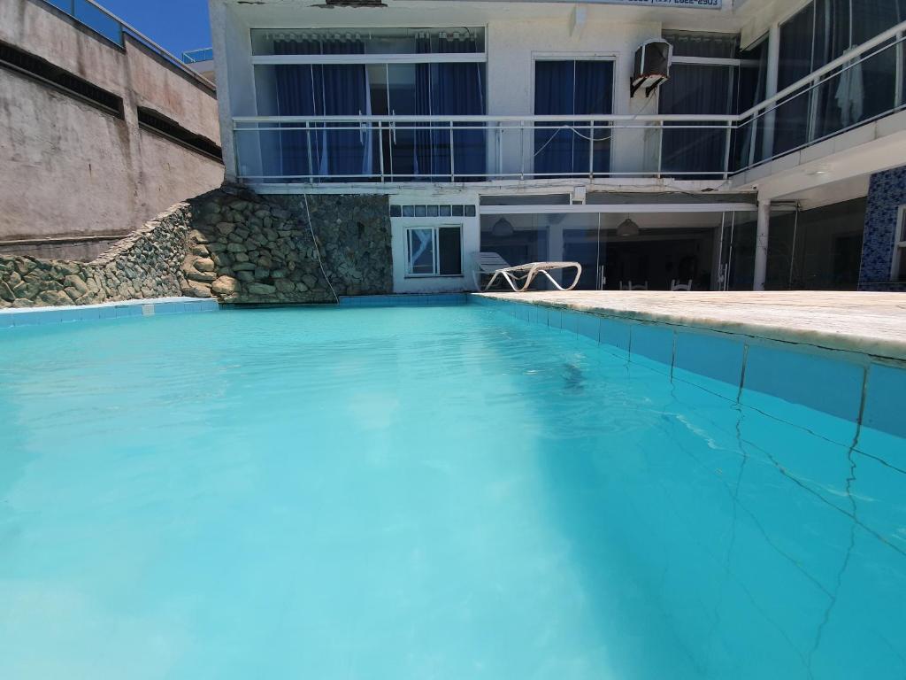 a swimming pool with blue water in front of a building at Pousada Seven in Arraial do Cabo