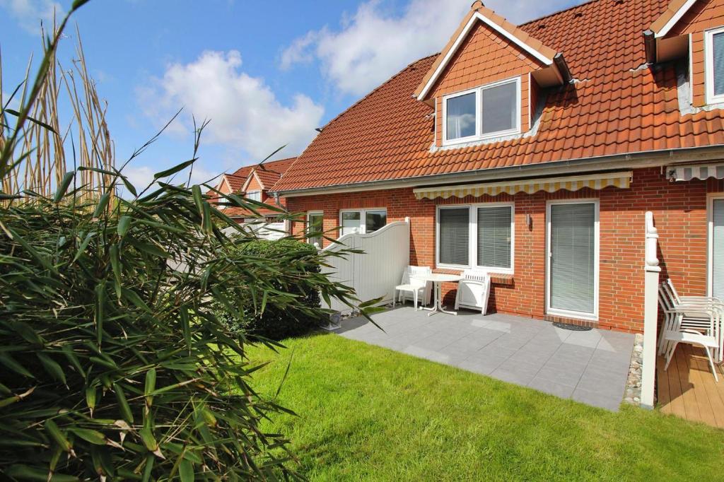 a red brick house with a patio and lawn at Terraced house, St Peter-Ording in Westereck