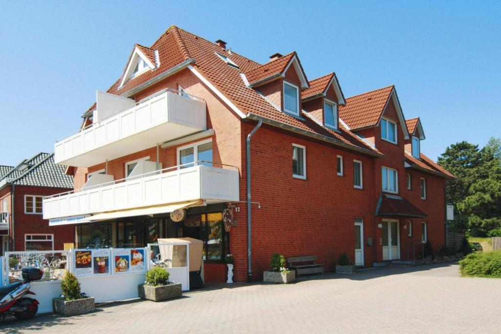 - un grand bâtiment en briques rouges avec un balcon blanc dans l'établissement Apartment, St Peter-Ording, à Sankt Peter-Ording
