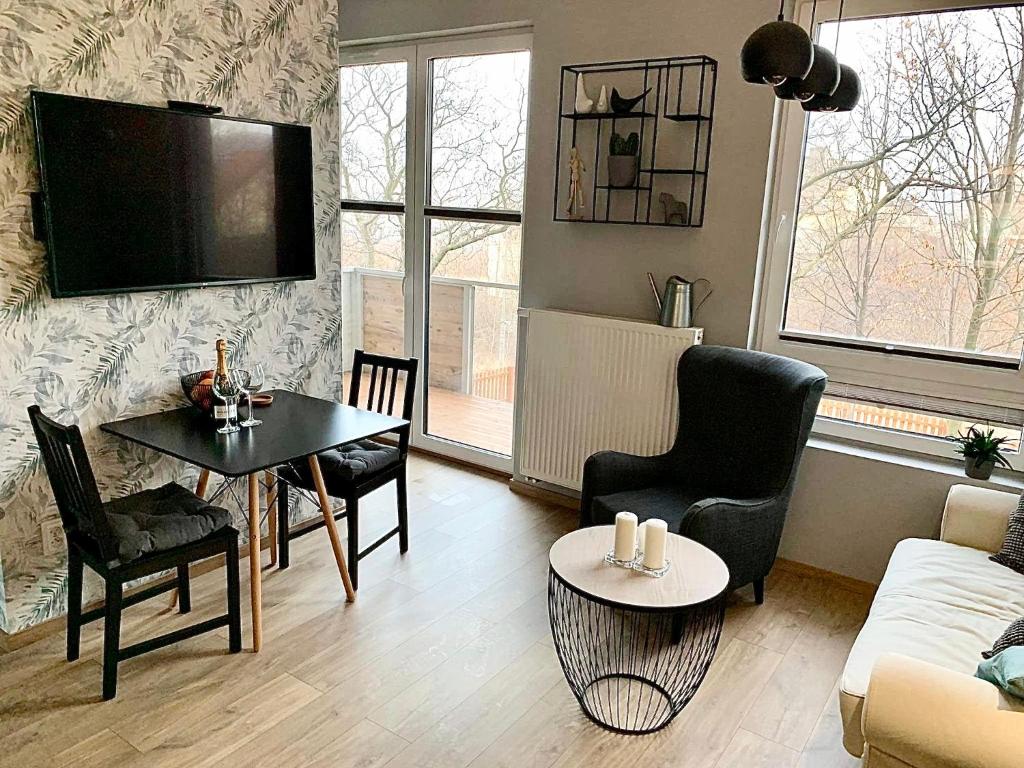 sala de estar con TV, mesa y sillas en Apartament Urodzajna en Bielsko-Biala