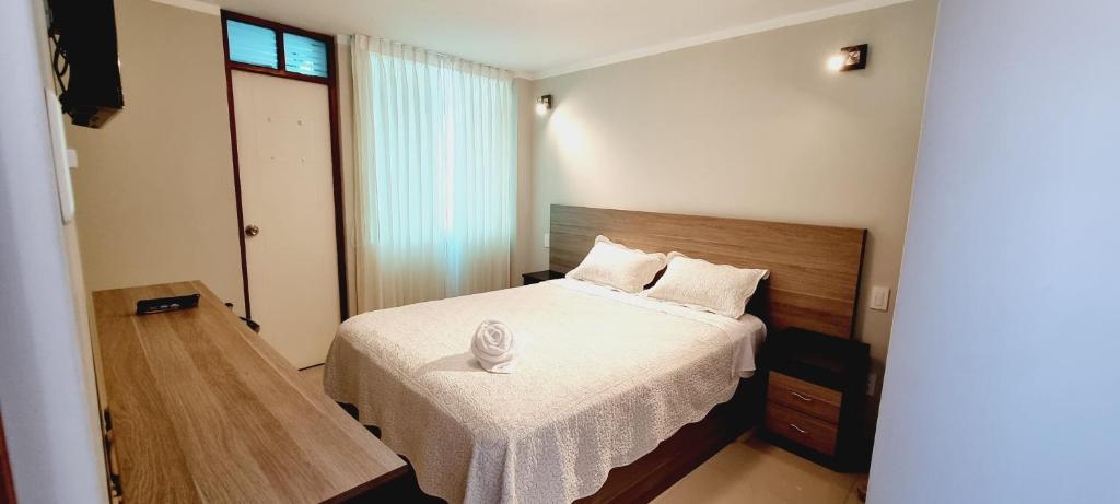 Dormitorio pequeño con cama con manta blanca en Hostal Montalvo en Moquegua