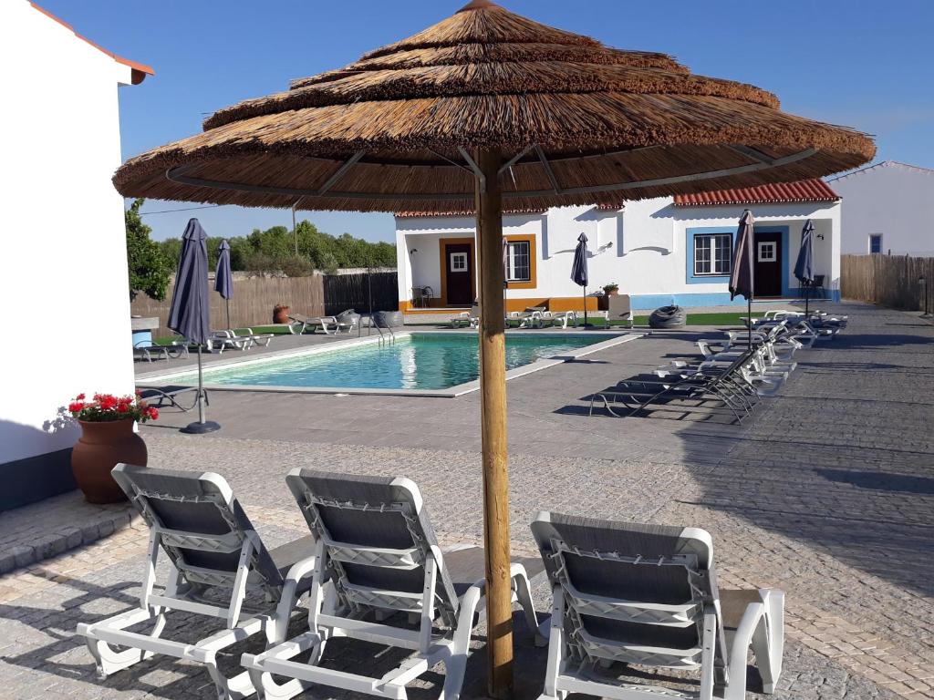 a group of chairs under an umbrella next to a pool at Casas da Minh'Alma in Reguengos de Monsaraz