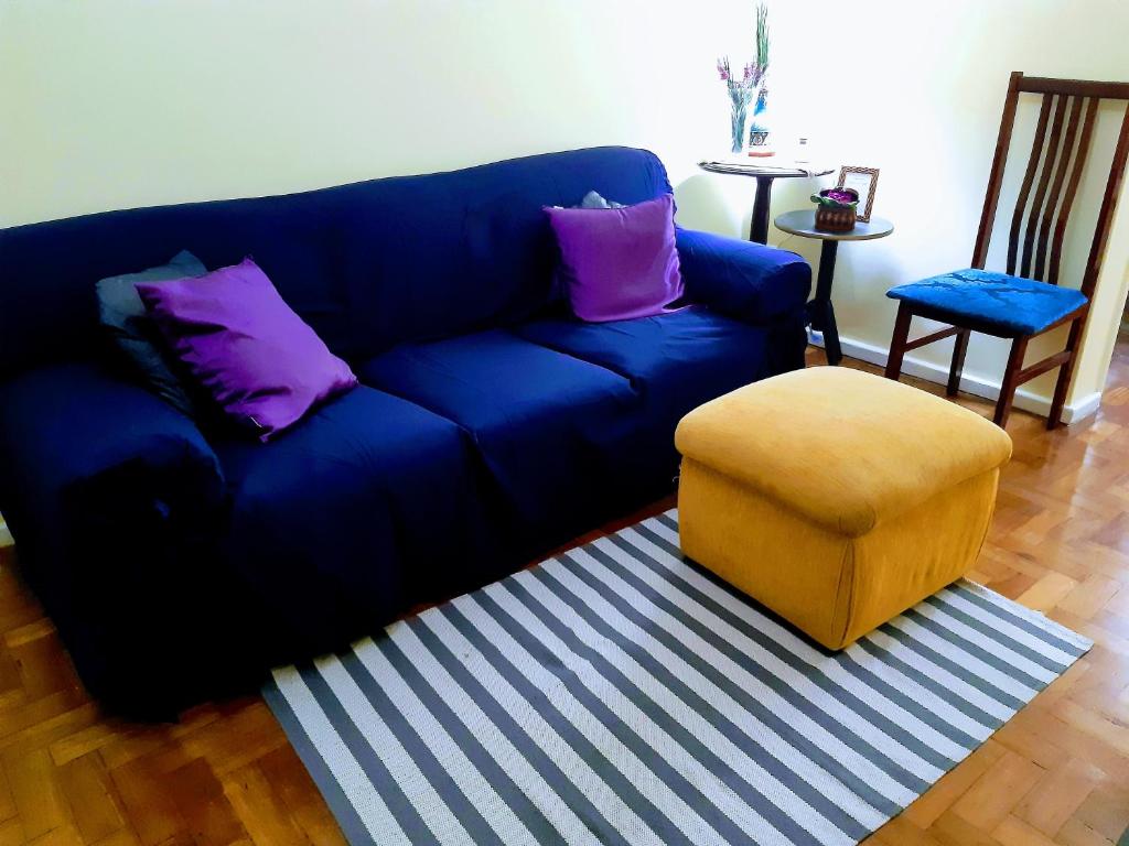Sofá azul con almohadas moradas y taburete en Apartamento Premium, en Río de Janeiro