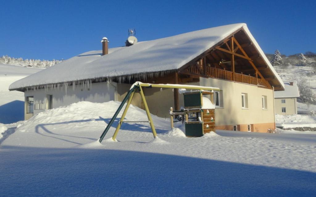 a playground in the snow in front of a building at Les Chantenées in La Bresse