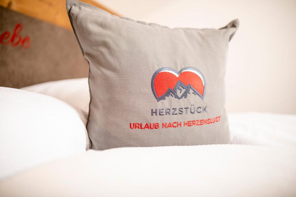 Una almohada en una cama con un parche en el corazón en Herzstück Appartements Zillertal en Kaltenbach