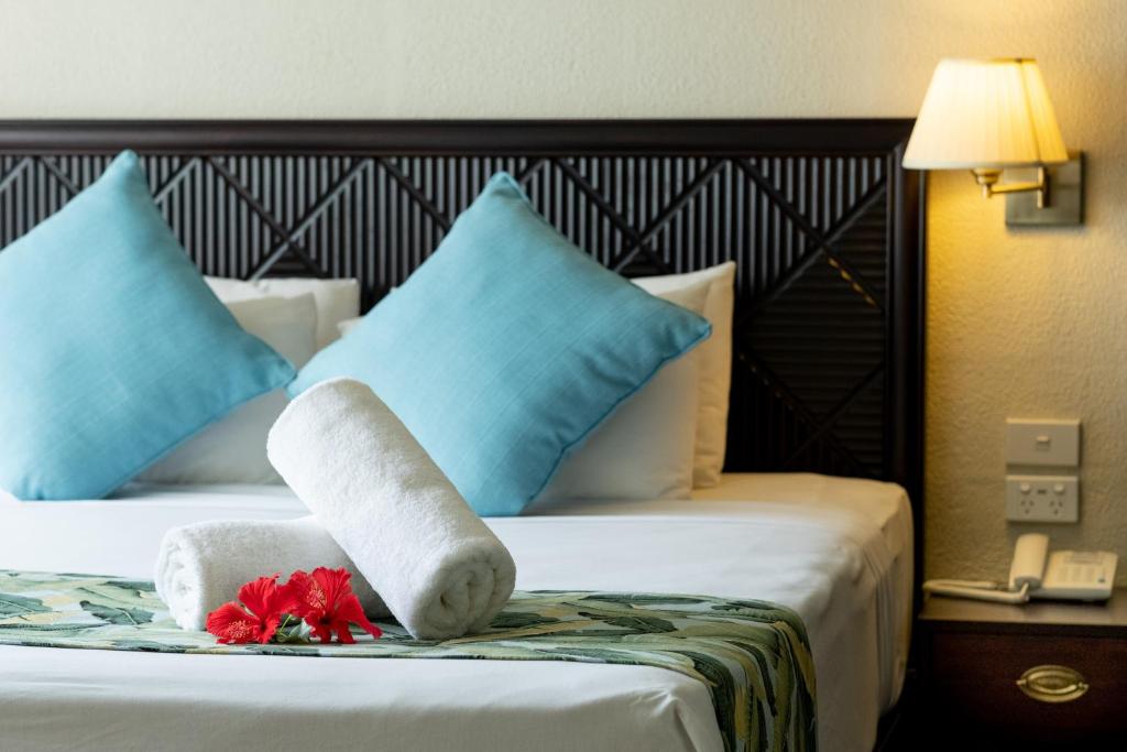 a hotel room with two beds with blue pillows at Fiji Gateway Hotel in Nadi
