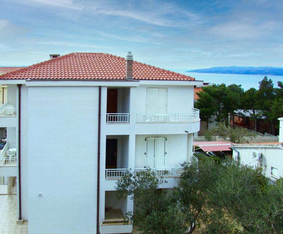 um edifício de apartamentos branco com telhado vermelho em Apartments Miranda Sea & Nature em Makarska