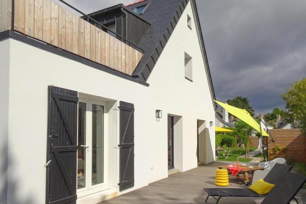 een wit huis met zwarte deuren en een patio bij Holiday Home, La Trinite-sur-Mer in La Trinité-sur-Mer