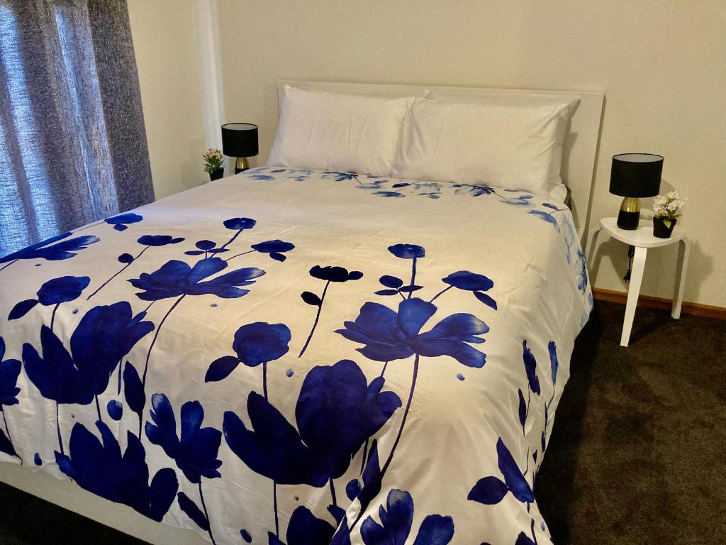 a bed with a blue and white comforter on it at CandE on Buller in Kingscote