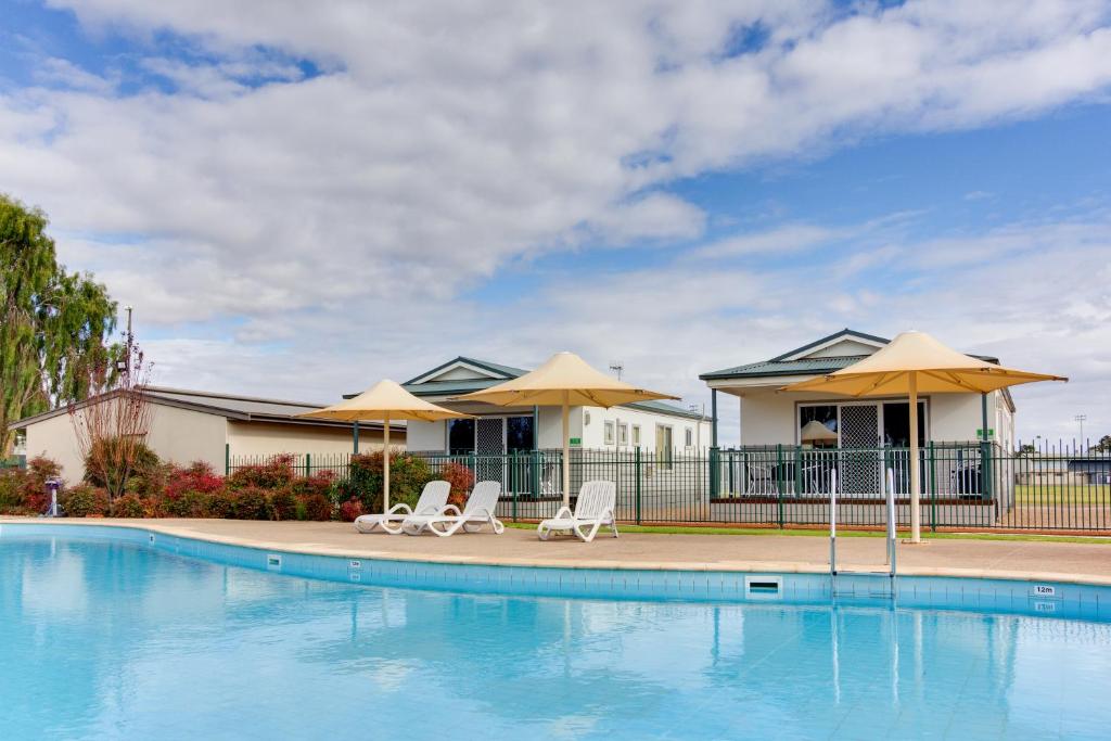 a swimming pool with two chairs and umbrellas at Berri Riverside Holiday Park in Berri