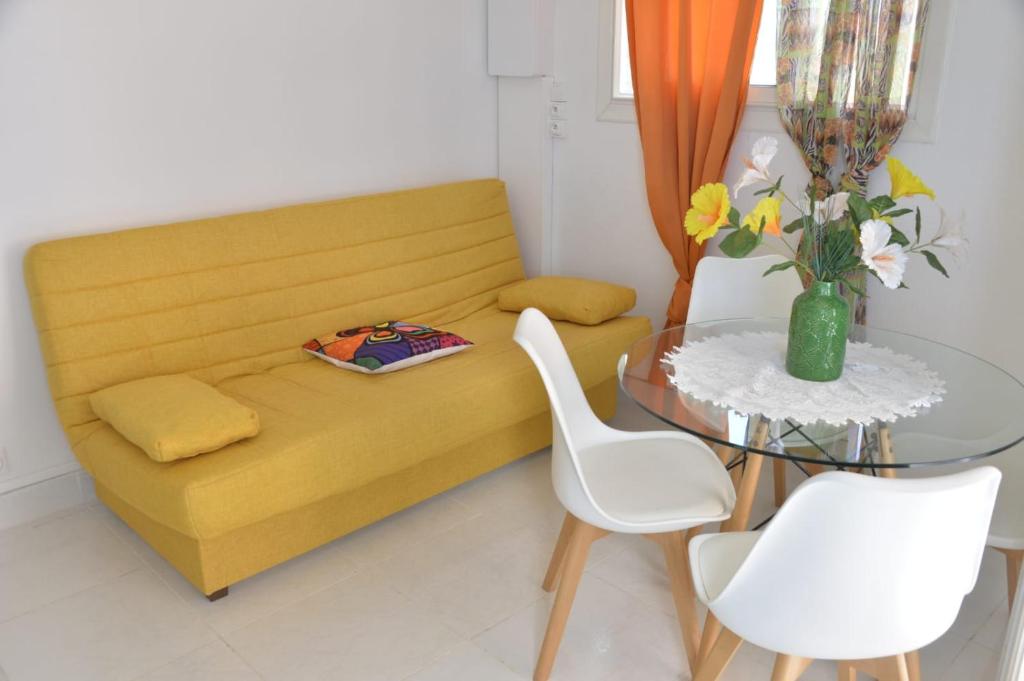 a living room with a yellow couch and a glass table at Studio Hibiscus in Petit-Bourg