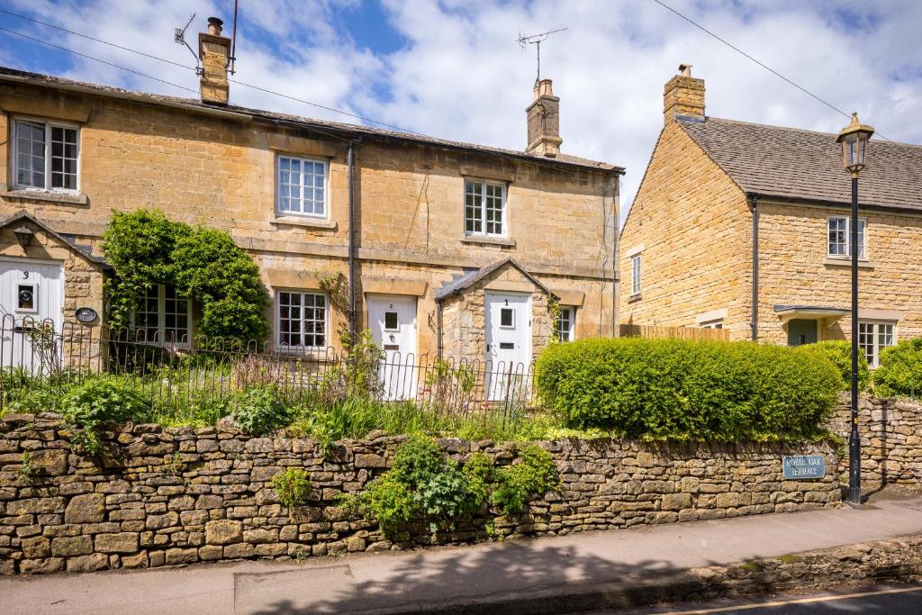 an old brick house with a stone wall at Royal Oak Cottage in Chipping Campden