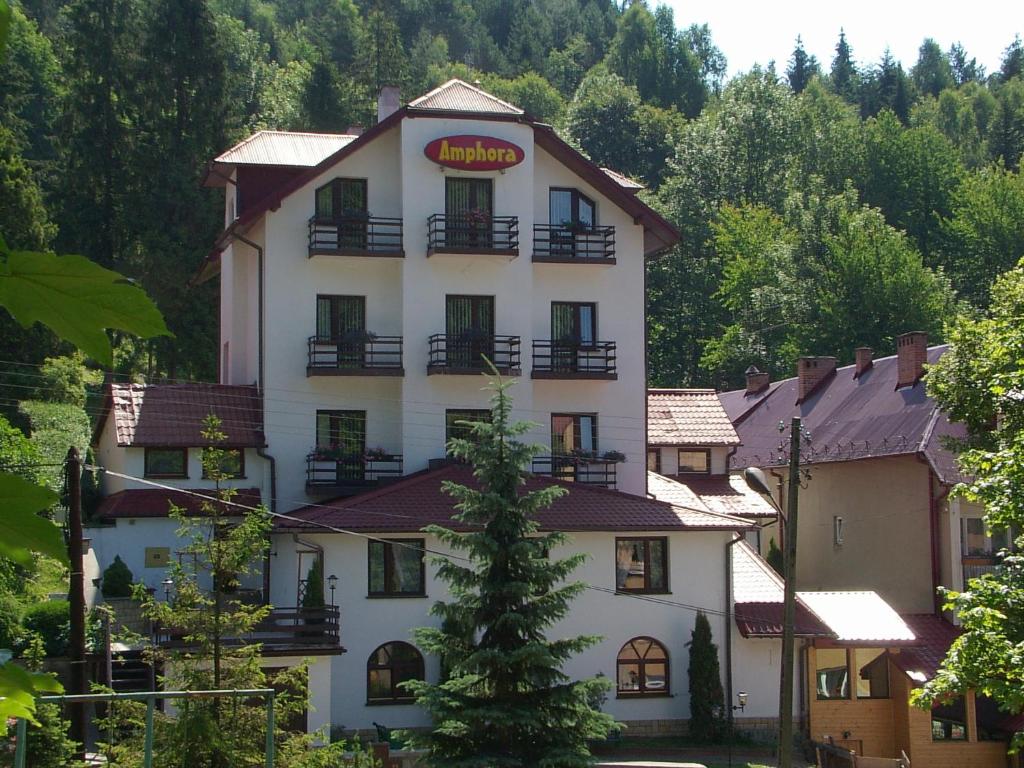 a large white building with a sign on it at Amphora Kompleks Wypoczynkowy in Krynica Zdrój