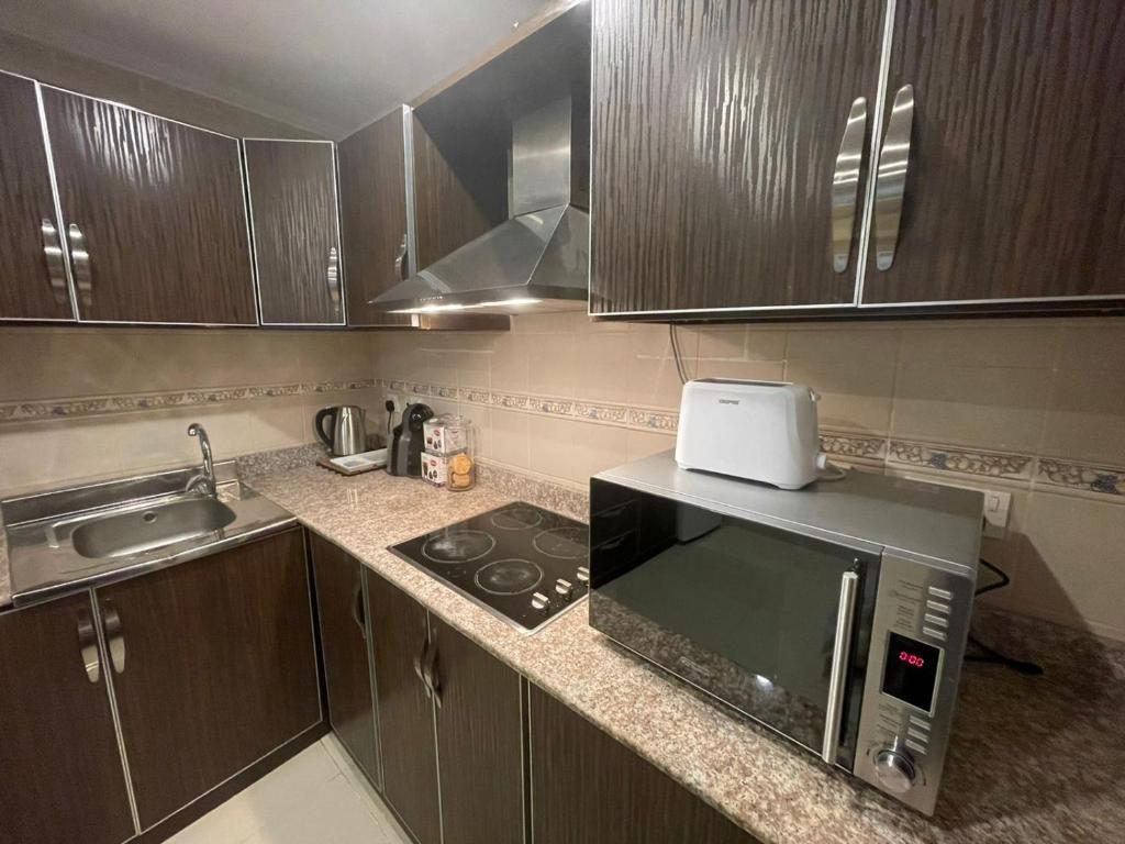 a kitchen with a microwave and a sink at sun sets for family only in Durat  Alarous