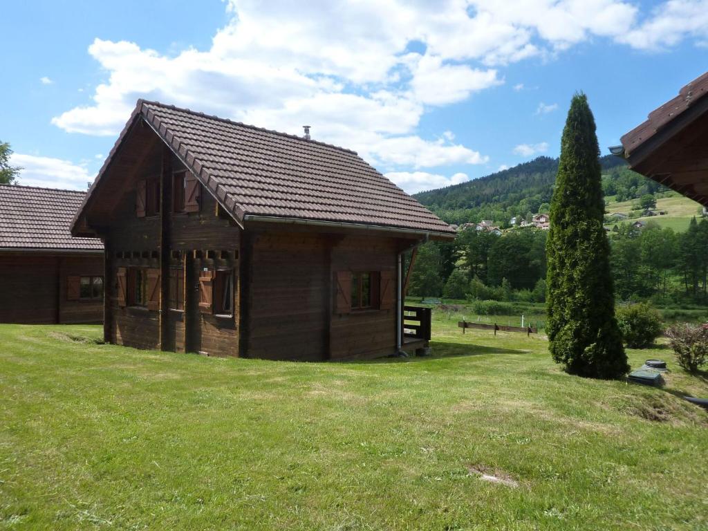 ein kleines Holzhaus auf einem Feld mit einem Baum in der Unterkunft Wooden chalet in Vosges by a pond in Zhezdi