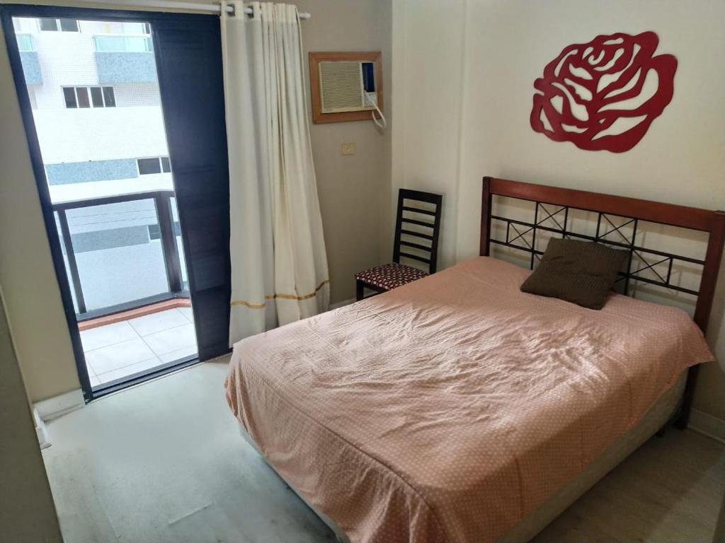 a bedroom with a bed and a large window at Apto frente à praia - Guilhermina in Praia Grande