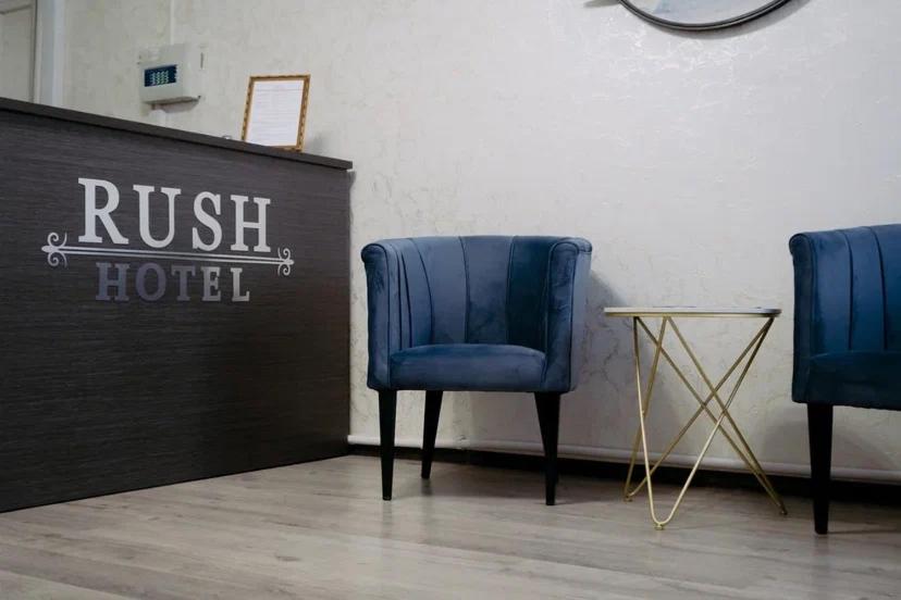 two blue chairs in a room with a hotel sign at Rush Hotel in Atyraū