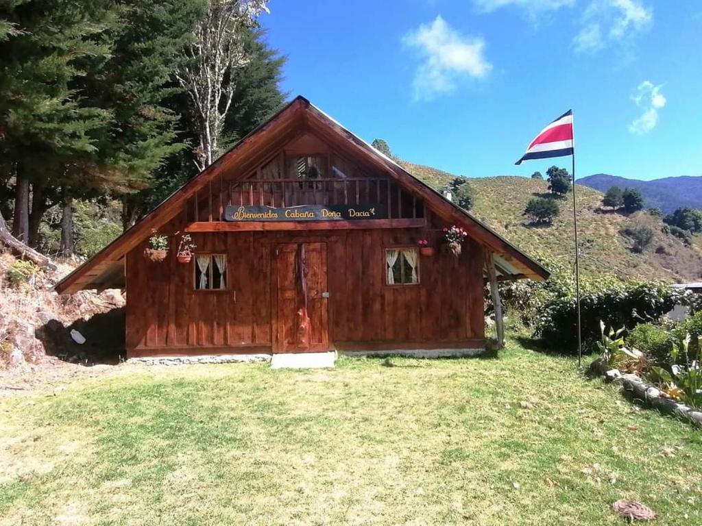 uma cabana de madeira com uma bandeira à sua frente em Cabaña Doña dacia em Alaska