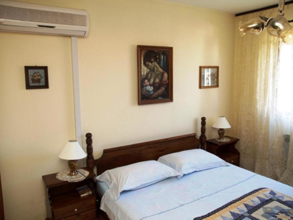 a bedroom with a bed with two lamps and a painting at Guest House Foretić in Dubrovnik