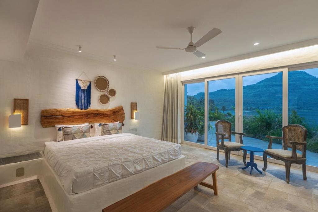 a bedroom with a bed and a large window at SaffronStays Kairos Athena, Karjat - Greek style pool villa near Camp Max in Karjat