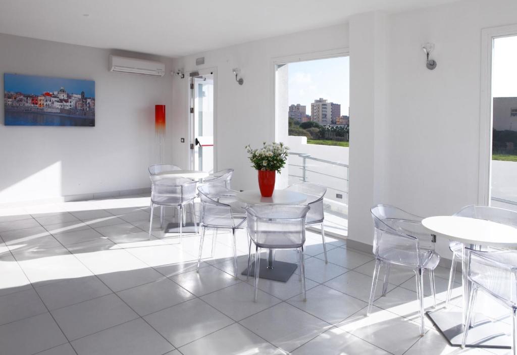 a white room with white tables and chairs and windows at Brezza Di Grecale in Trapani