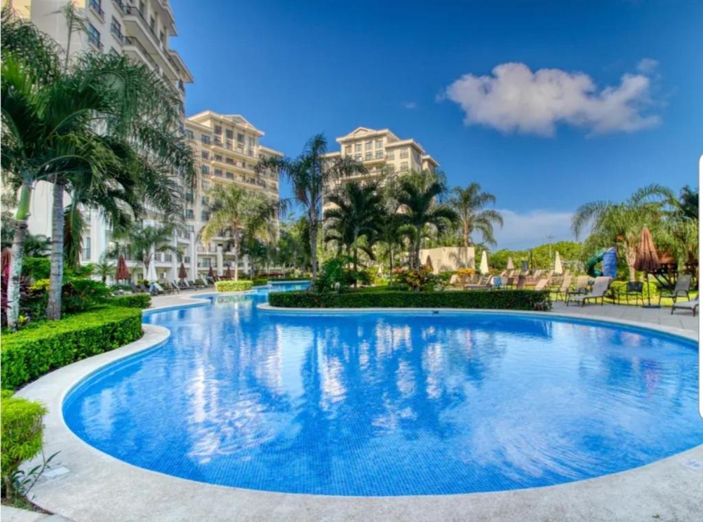una piscina en un complejo con palmeras y edificios en The Best Ocean and Mountain views in the city, en Jacó