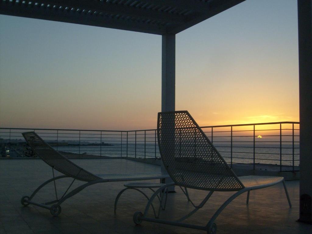 two chairs sitting on a balcony with the sunset at Brezza Di Grecale in Trapani