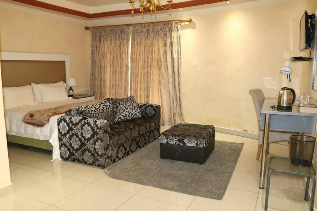 ein Schlafzimmer mit einem Bett, einem Sofa und einem Stuhl in der Unterkunft Sibebe Resort in Mbabane