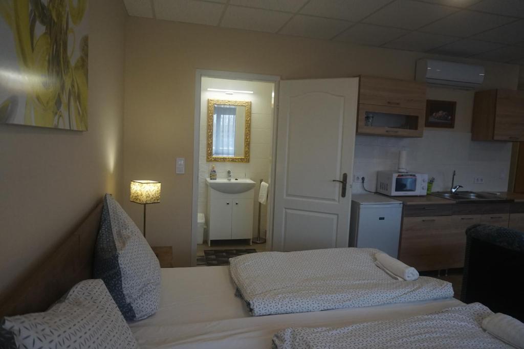 Habitación con cocina con cama y lavamanos en Hotel Ajka Üzletház Panzió Ajka, en Ajka
