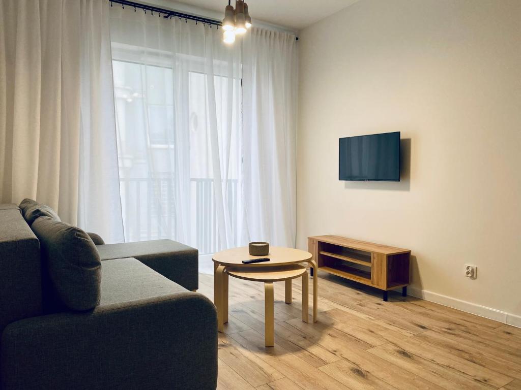 uma sala de estar com um sofá, uma mesa e uma televisão em Apartment Insat II em Szczecin