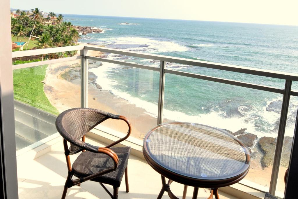 two chairs and a table on a balcony overlooking the ocean at Apartment L4-5, Oceanfront Condos, Galle, Sri Lanka in Galle