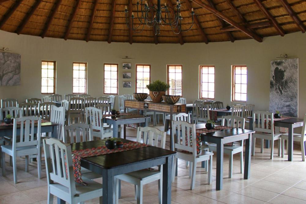 a dining room with tables and white chairs at Bayala Private Safari Lodges in Hluhluwe