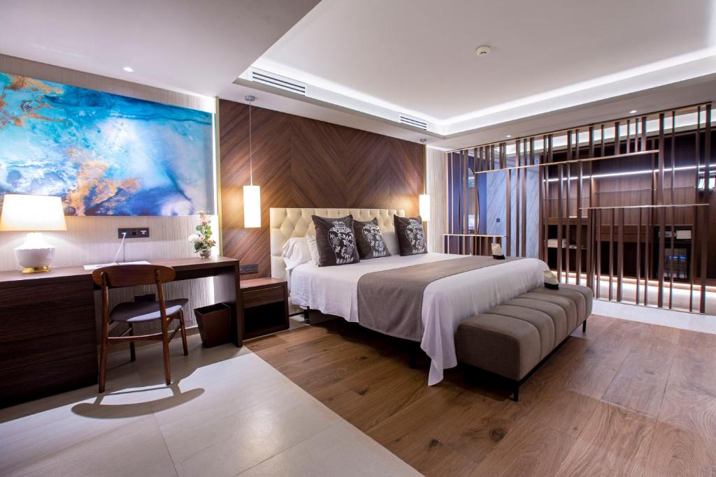 sypialnia z dużym łóżkiem i biurkiem oraz łóżko o wymiarach 6 x 6 x 6 w obiekcie Panafrica Hotel Boutique & Spa w Bacie