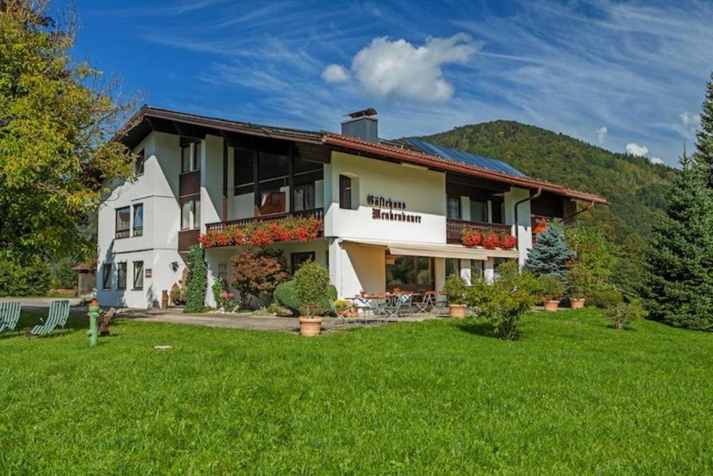 ein großes weißes Haus mit grünem Rasen in der Unterkunft Gästehaus Menkenbauer in Ruhpolding