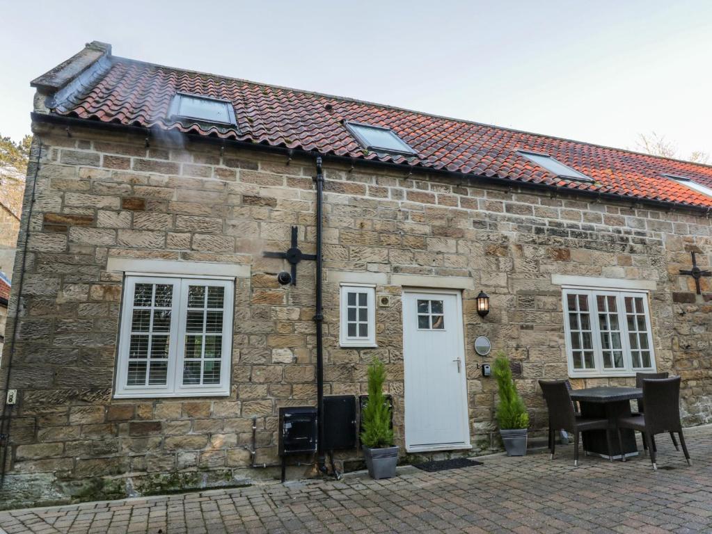 a stone cottage with a table and chairs in front of it at Clematis Cottage in Whitby