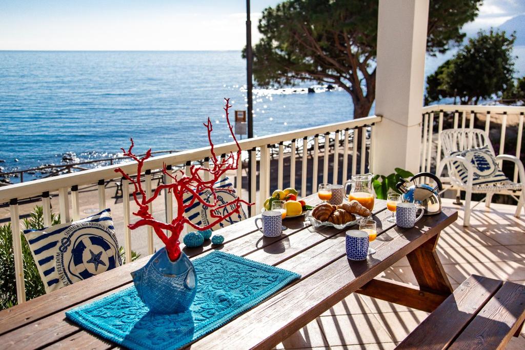 a table with food and drinks on a balcony with the ocean at Terrazza Lungomare, e sei in spiaggia... in Cala Gonone