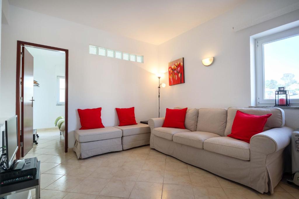 una sala de estar con 2 sofás y almohadas rojas en Rua 1 de Maio, en Luz