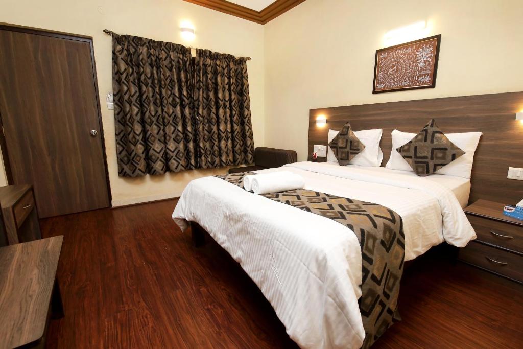 a hotel room with two beds and a window at Westend Hotel in Matheran