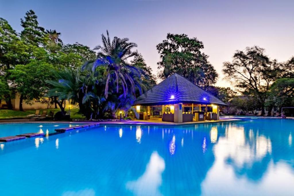 a swimming pool with a gazebo at night at Sanbonani Hotel in Hazyview