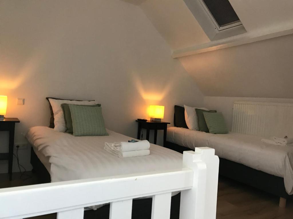 duas camas num pequeno quarto com duas lâmpadas em cafe 't Vonderke em Eindhoven